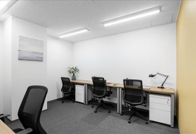 Shared workspace with three desks, black mesh chairs, and white storage pedestals.