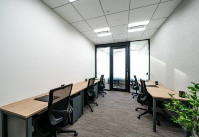 Modern workspace with long timber desks and glass partitioning leading to a private area.