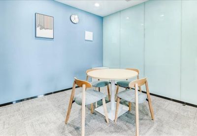 Small break area featuring a round table and four chairs against a soft blue feature wall.