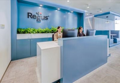 Professional reception desk area with wood accents, potted greenery, and corporate branding.