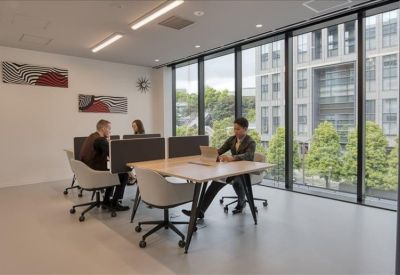 Meeting room with a large wooden table, teal chairs, and warm pendant lighting.