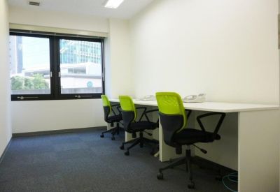 Bright office space with white desks, lime green ergonomic chairs, and city views.