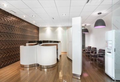Breakout area with modern white curved workstations and dark wood flooring.