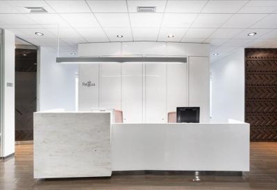 Minimalist white reception desk on a warm wood floor.