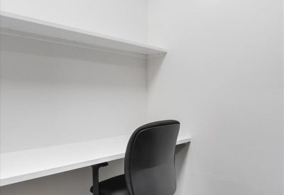 Private white-walled workstation with a built-in desk and black swivel chair.