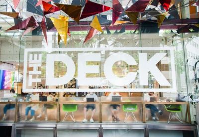 Large glass storefront window displaying the brand name The Deck with colorful geometric ceiling decorations.