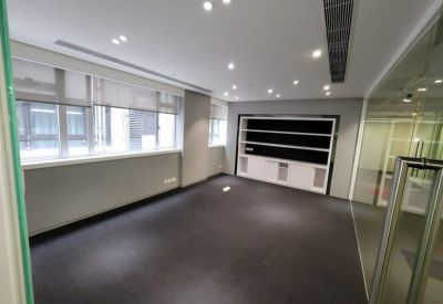 Empty private office suite with dark carpeting, large windows, and built-in shelving.