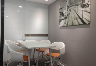 Small meeting room with a white table, orange-accented chairs, and city-themed wall art.
