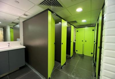 Modern restroom with lime green stall doors and dark grey partitions.
