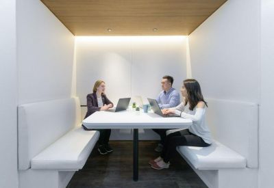Semi-enclosed meeting booth with plush white bench seating and a wooden ceiling.