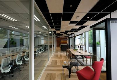 Modern coworking corridor with glass walls, private booths, and a vibrant red chair.