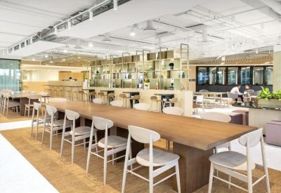 Vibrant communal dining area with a long wooden table, white chairs, and a modern cafe-style background.