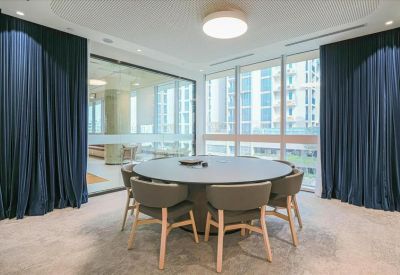 Modern circular meeting room with dark blue privacy curtains and a round black table.