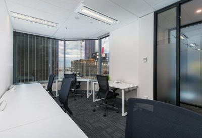 Bright corner office with white desks and floor-to-ceiling windows.