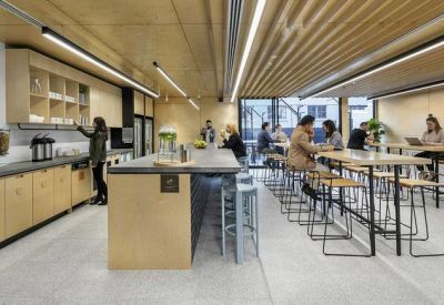 Spacious communal kitchen and dining area with light wood finishes and long high-top tables.