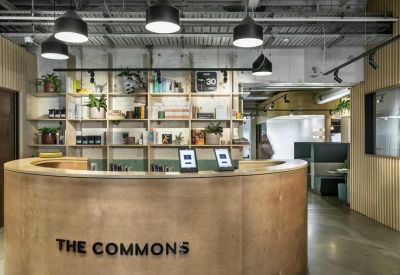 Curved wooden reception desk with branded signage and floating shelves in a modern lobby.