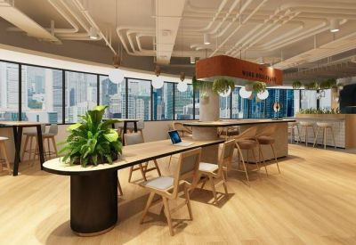Spacious coworking area with long wooden tables, ergonomic chairs, and large windows.