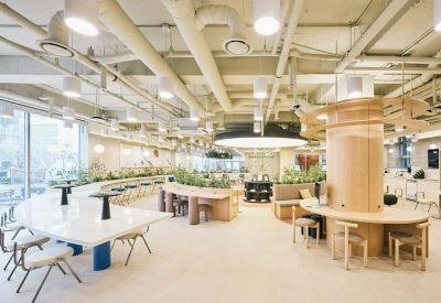 Sunlit open-plan workspace with curved desks, wooden pillars, and plenty of natural light.