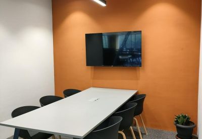 Meeting room with an orange feature wall, white table, and wall-mounted monitor.