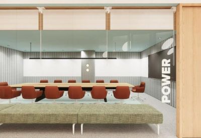 Professional boardroom with a long wooden table and orange ergonomic chairs.
