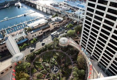 Aerial view of a circular landscaped garden and waterfront promenade near the building.