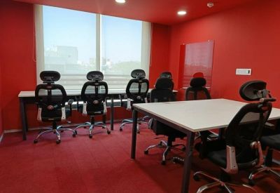 Vibrant red private office room with ergonomic black chairs and large window.
