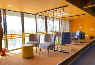 Cozy breakout area with grey armchairs, a yellow ottoman, and a decorative rope partition.