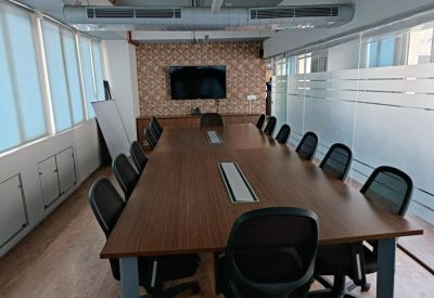 Large wooden boardroom table surrounded by black chairs in a professional meeting room.