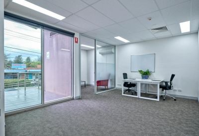Bright open office space with large windows and a white workstation.