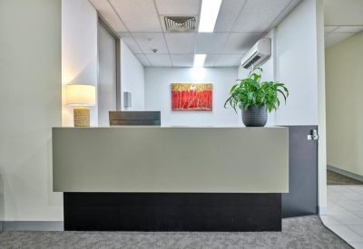 Modern minimalist reception desk featuring a green potted plant and abstract red wall art.
