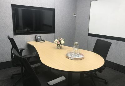 Small meeting room with a teardrop-shaped table and wall-mounted screen.