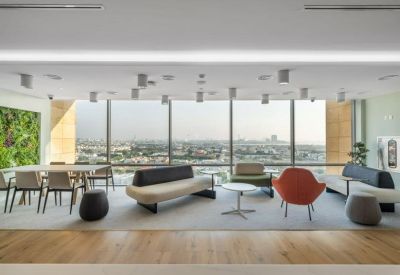 Spacious lounge area with modern sofas, colorful armchairs, and floor-to-ceiling windows overlooking the city.