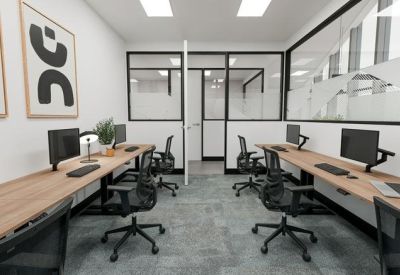 Professional workspace with long wooden desks and ergonomic black chairs.