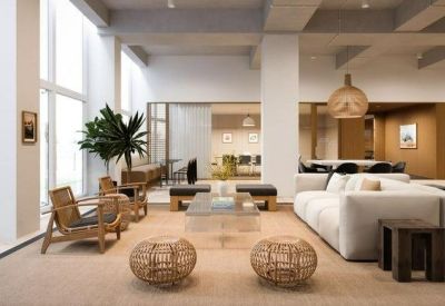 Spacious communal lounge with a large sectional sofa, wicker chairs, and tall windows.