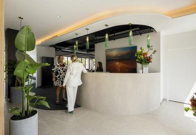 Modern reception area with a curved stone desk, hanging pendant lights, and indoor plants.