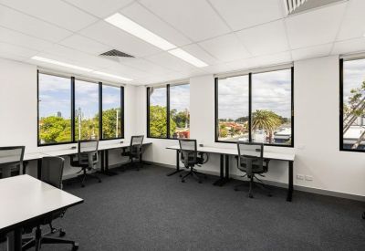 Bright private office suite featuring white desks, ergonomic mesh chairs, and large windows.