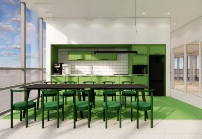 Modern communal kitchen area with vibrant green cabinetry and a long dining table.