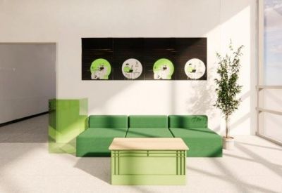 Bright reception area featuring a green sectional sofa and unique wall art with record motifs.