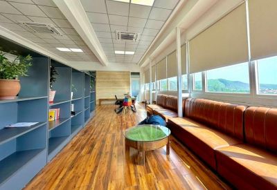 Spacious breakout area with leather sofas, wooden floors, and a green coffee table.