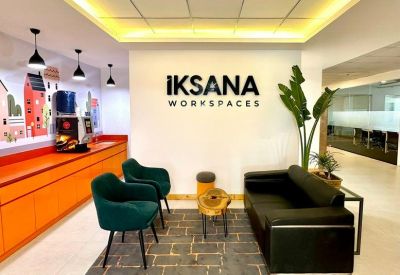 Reception lounge area with green velvet armchairs and a modern black leather sofa.