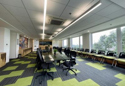 Large training room with rows of tables, black chairs, and bright green carpeting.