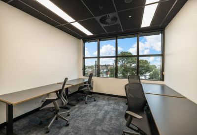 Private four-person office suite with a large window and grey carpet.