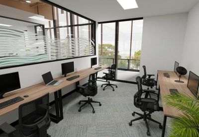 Private glass-walled office suite with long wooden desks and natural light from large windows.