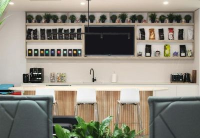 Bright breakout space featuring a long wooden table and shelves stocked with coffee.