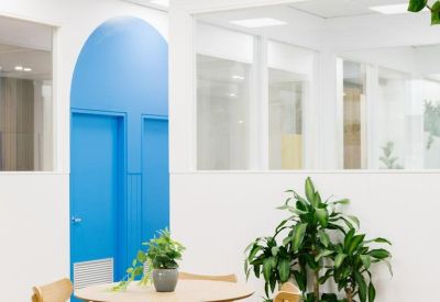 Bright dining area with light wood table, chairs, and vibrant blue arched wall.