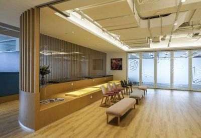 Bright breakout area with wooden slat walls, bench seating, and an industrial ceiling.