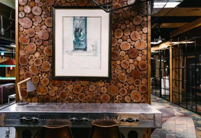 Workstation with a metal desk set against a feature wall of stacked wood logs.