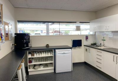 Office kitchen and breakroom featuring white cabinetry, a dishwasher, and a coffee station.