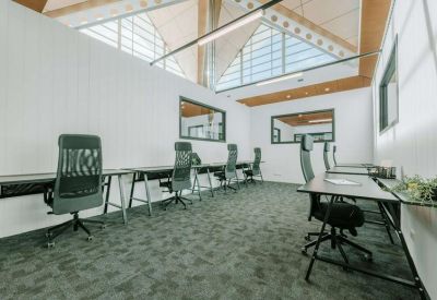 Open-plan office with multiple workstations, ergonomic mesh chairs, and high vaulted ceilings.