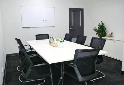 Meeting room with whiteboard and black chairs around a long table.
